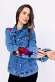 Modelo Simone veste jaqueta jeans arabescos na cor azul. Peça bordada manualmente com paetês e pedrarias de diversas cores.