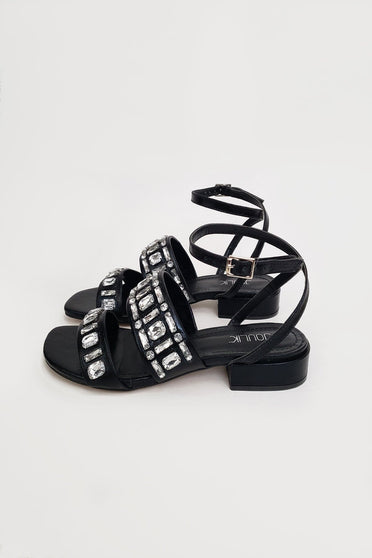Foto em estilo still da sandália lumi. Sapato de couro na cor preta, possui tira ajustável no tornozelo por fivela de metal.