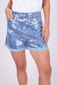 A modelo veste shorts vitru na cor azul. Peça com paetês transparentes escamados bordados à mão. Ideal para usar no dia a dia