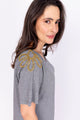 Modelo Simone está vestindo blusa bordada tully na cor mescla. Peça com bordado de strass e vidrilhos na região dos ombros.