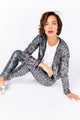 Modelo Michela está sentada no chão e usa calça luna grafite com prata e casaqueto bordado luna na mesma cor. Feito no Brasil