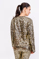 Modelo Simone está de costas e usa casaqueto bordado luna na cor dourado. Peça ideal para usar em festas, shows e eventos.