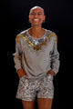 Modelo Fernanda usa shorts luna com bordado manual de paetês na cor prata. Peça ideal para usar com jaqueta, blusa ou regata.