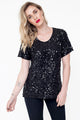 Modelo Juliana está vestindo blusa luna preta. Peça com bordado salpicado de paetês, é feita de malha e muito confortável.