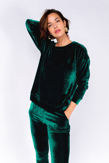 Modelo Michela está vestindo blusa de veludo velvet na cor verde. Peça muito confortável com tecido de veludo e manga longa.