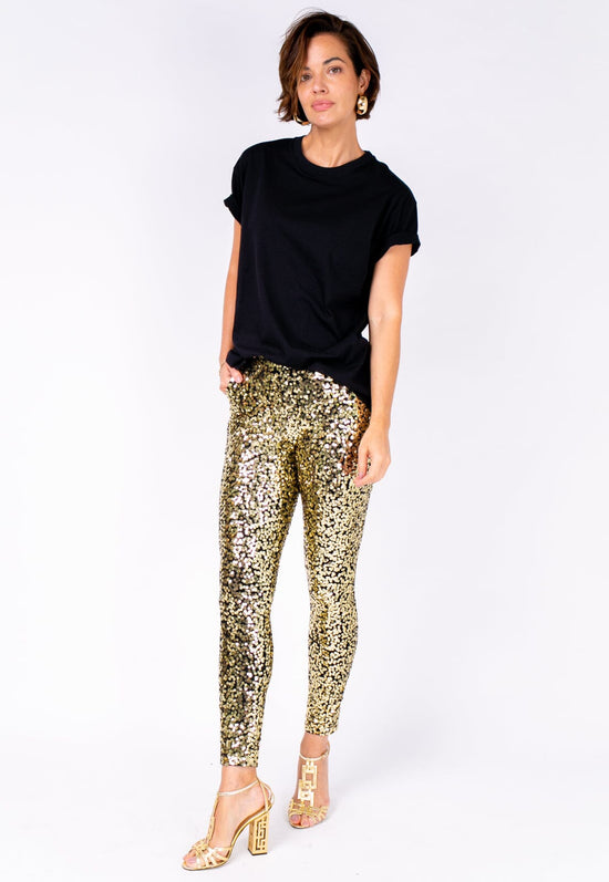 Modelo Michela veste calça luna dourada e blusa na cor preta. Modelo ideal para usar para sair de noite ou ir em eventos.