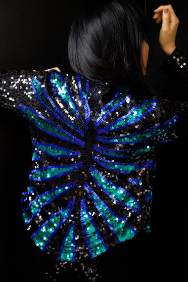 Modelo Katy está de costas e usa casaqueto ava azul e verde. Peça confortável, inteiramente bordada com paetês e pedrarias.