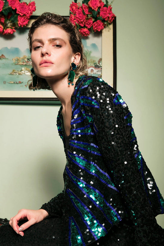 Modelo Joana está vestindo casaqueto ava nas cores azul e verde. Peça com muito brilho de paetês e pedrarias bordados à mão.