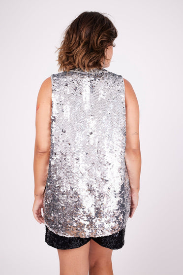 Modelo Victoria está de costas e usa colete bordado ayla com paetês na cor prata. Peça ideal para usar em festas e eventos.
