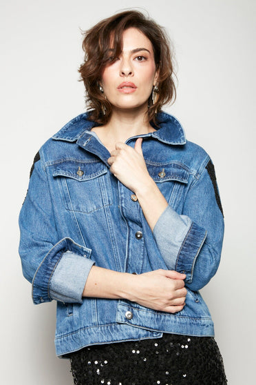 Modelo Isabel usa jaqueta jeans logus colorida. Possui fechamento de botões de metal, bolsos nas laterais e bolsos internos.