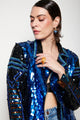 Modelo Isabel usa jaqueta bordada ailuros azul. Peça com modelagem no estilo perfecto, possui fechamento por zíper de metal.