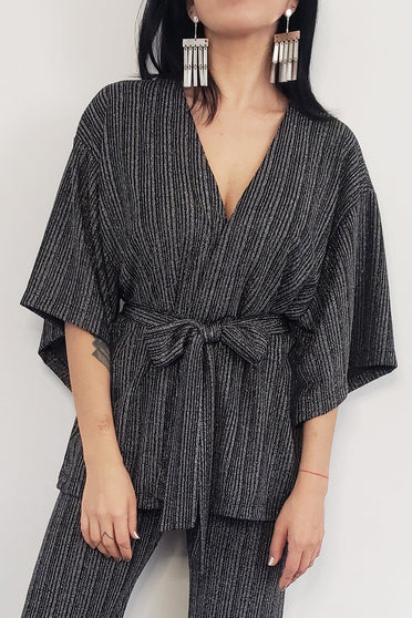 Modelo Katy veste kimono tyler na cor prata. Peça de malha lurex com muito brilho, acompanha uma faixa avulsa de mesma cor.