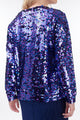 Modelo Juliana está de costas e vestindo blusa sole de manga longa. Peça com muito brilho de paetês nas cores azul e fúcsia.
