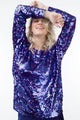 Modelo Juliana usa blusa de manga longa sole nas cores azul e fúcsia. Bordado escamado feito inteiramente à mão com paetês.