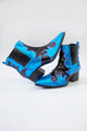 Lateral da bota Waves na cor azul e preto. Calçado estilo caubói em couro e couro metalizado. Possui salto pequeno.