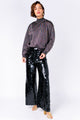 Modelo em pé usando calça pantalona sole prata Joulik. Peça handmade com paetês na cor preto. Ideal para ser usado em eventos