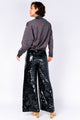 Modelo de costas usando calça pantalona bordada à mão de brilho para usar em festas e eventos handmade com paetês preto.