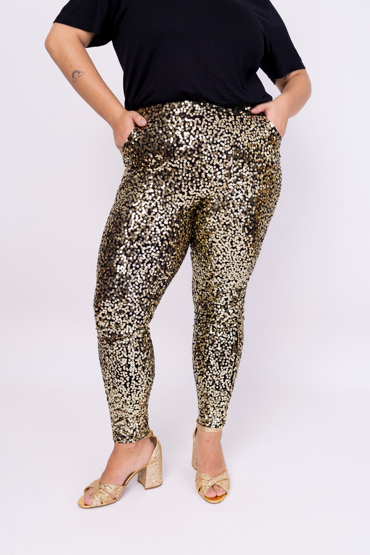 Modelo Victoria veste calça skinny bordada luna na cor dourada. Peça feita no Brasil, possui bordado salpicado com paetês.