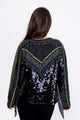Modelo Simone está de costas e usando casaqueto bordado onix preto. A peça possui franja de miçanga nas costas e nas mangas.