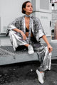  Modelo usando Faixa Luna grafite com prata, Kimono Eris prata e Calça pantalona sole prata. Peças com muito brilho de paetês.