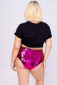 Modelo Victoria está de costas e usa hot pant zíni vermelha e pink. Peça ideal para usar e arrasar em festas, shows e eventos