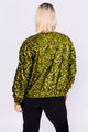 Modelo Victoria está de costas e usando jaqueta bomber bordada eris verde musgo. Ideal para usar em festas, shows ou eventos.
