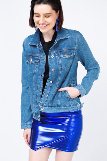 Modelo Juliana usa jaqueta jeans basik azul, possui bolsos e fechamento com botões de metal nos punhos e na frente da peça.