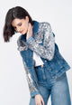 Modelo veste jaqueta jeans azul timu com o bordado feito manualmente de paetês de cor prata ideal para eventos