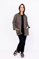 Modelo Simone está vestindo jaqueta parka bordada beija-flor na cor verde. Peça super confortável, ideal para compor looks.