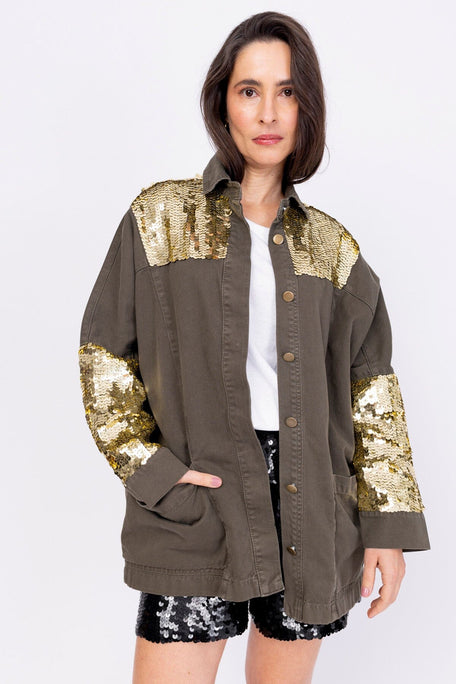 Modelo Simone está usando jaqueta parka gama dourada. Peça com bordado de paetês escamados nas mangas e na parte superior.