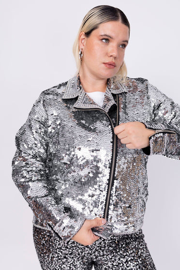 Modelo Victoria está vestindo jaqueta perfecto bordada lumi prata. Peça possui fechamento de zíper na frente e nas mangas.