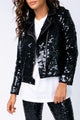 Modelo Nathália usa jaqueta nox preta, camiseta branca e calça preta. Jaqueta no estilo perfecto com bordado manual de paetês