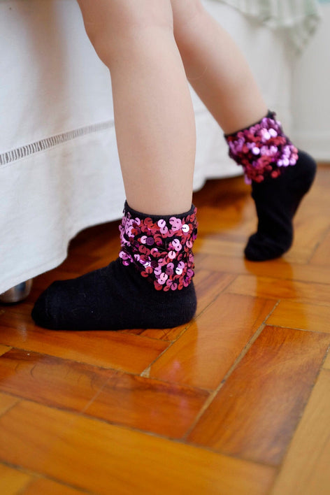 A criança usa a meia bordada luna infantil na cor rosa. Peça com bordado salpicado de paetês nos tornozelos.