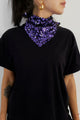Modelo está usando lenço bordado luna na cor roxo no pescoço e camiseta na cor preta. Acessório com muito brilho de paetês.