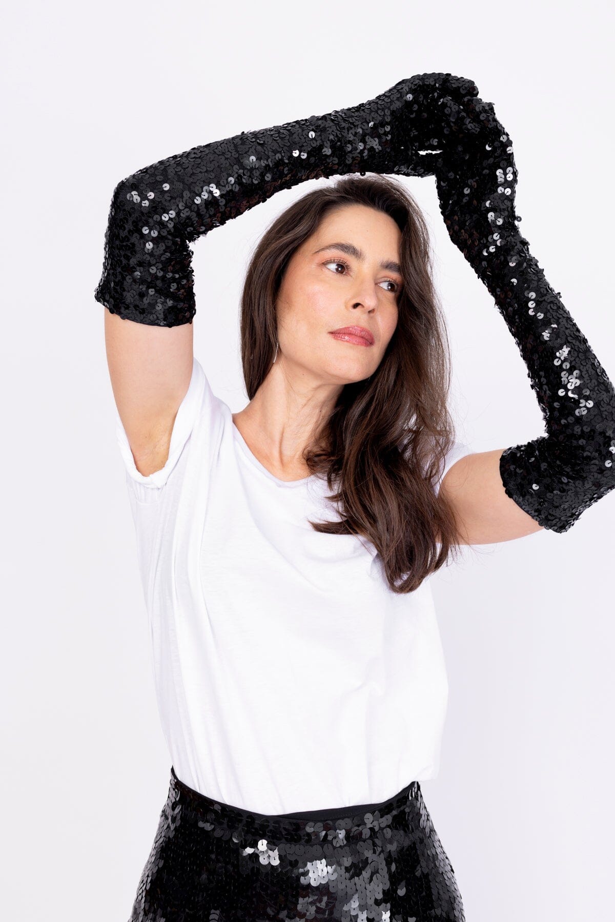 Modelo Simone está com as mãos para o alto enquanto usa a luva bordada luna cor preta. Acessório bordado inteiramente à mão.