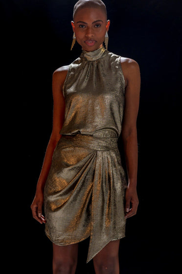 Modelo em pé usa conjunto Atenas na cor dourado. Peça com um ótimo caimento, é ideal para usar e arrasar no look.