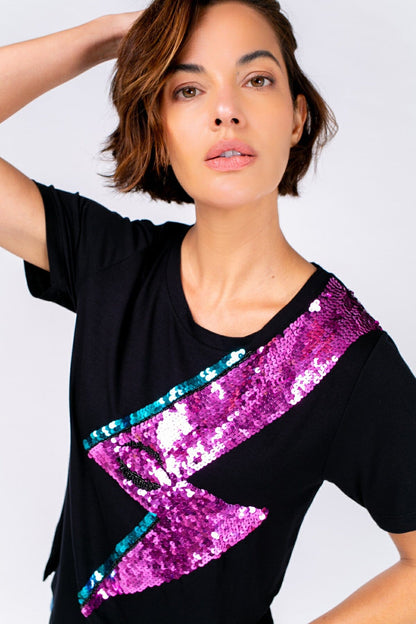 Modelo Michela veste blusa bowie preta. Peça possui um desenho de raio bordado com paetês. É ideal para usar em eventos.