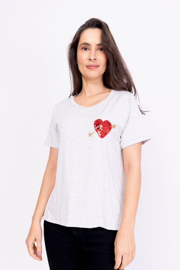Modelo Simone está usando blusa cupido mescla claro. Peça com bordado de paetês e pedrarias que formam um coração com flecha. 