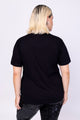 Modelo de costas veste tshirt bordada floyd na cor preto. Blusa de malha bordada com miçangas e paetês que formam desenhos.