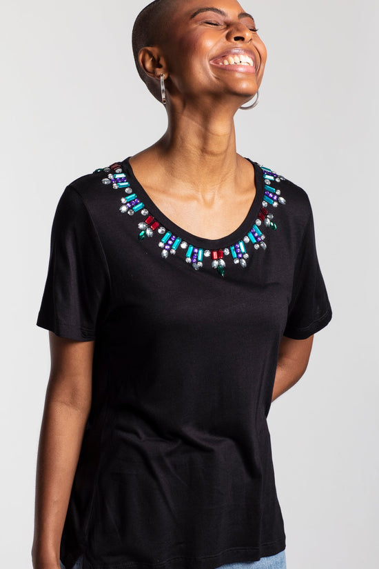 Modelo veste blusa Leonor preto. Peça de malha  com pedrarias colorida bordada manualmente na gola. Produto 100%  nacional.