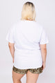 Modelo Victoria está de costas e usando blusa bordada love na cor branca. Peça perfeita para usar no dia a dia ou em passeios