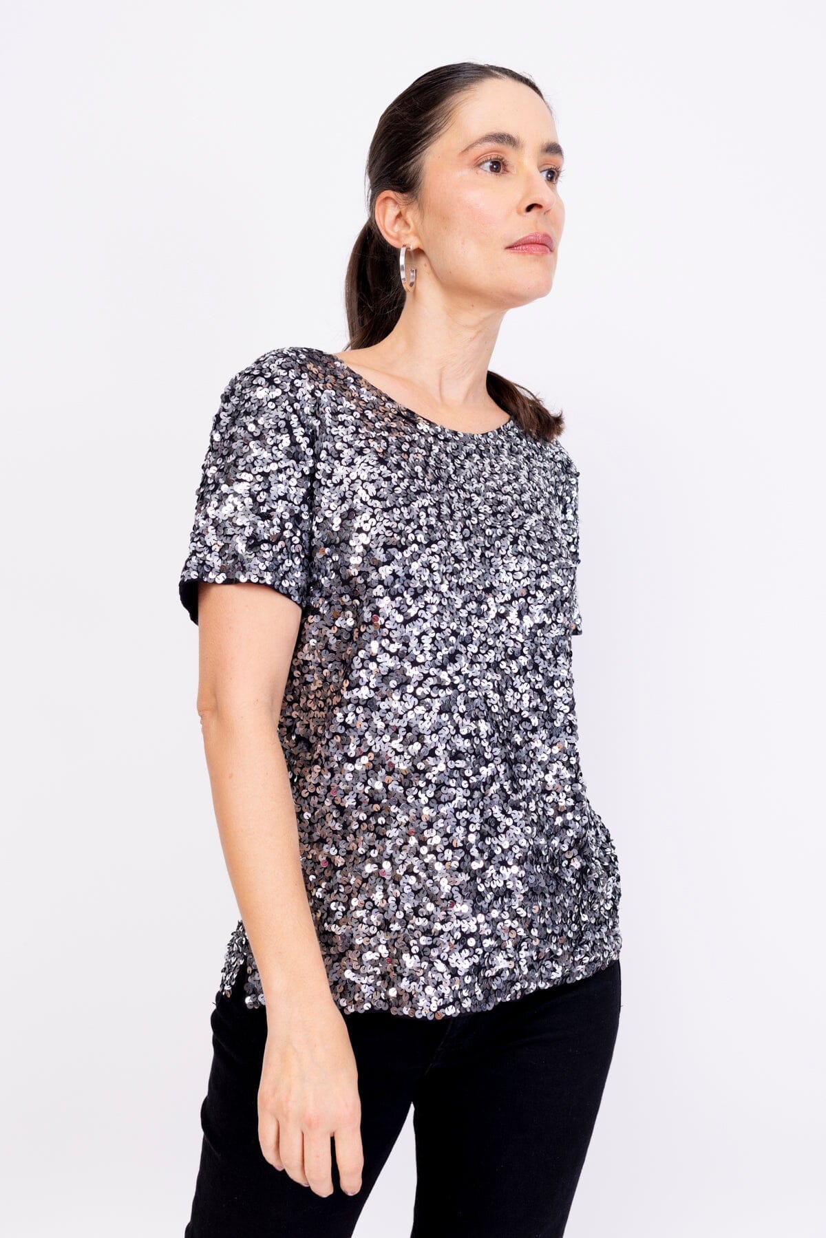 Modelo Simone usa blusa bordada luna na cor prata com grafite. Peça de malha com muito brilho de paetês bordados manualmente.