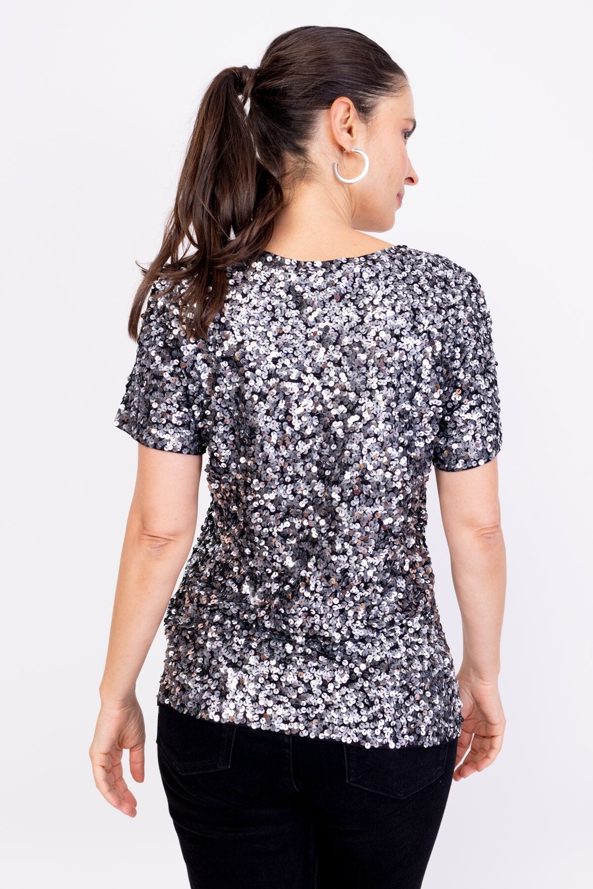 Modelo Simone está de costas e usa blusa bordada luna nas cores grafite com prata. Peça ideal para compor looks e arrasar. 