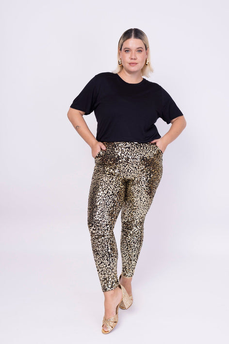 Modelo Victoria usa camiseta básica na cor preta e calça luna na cor dourada. Peça de viscose com elastano. Feito no Brasil.