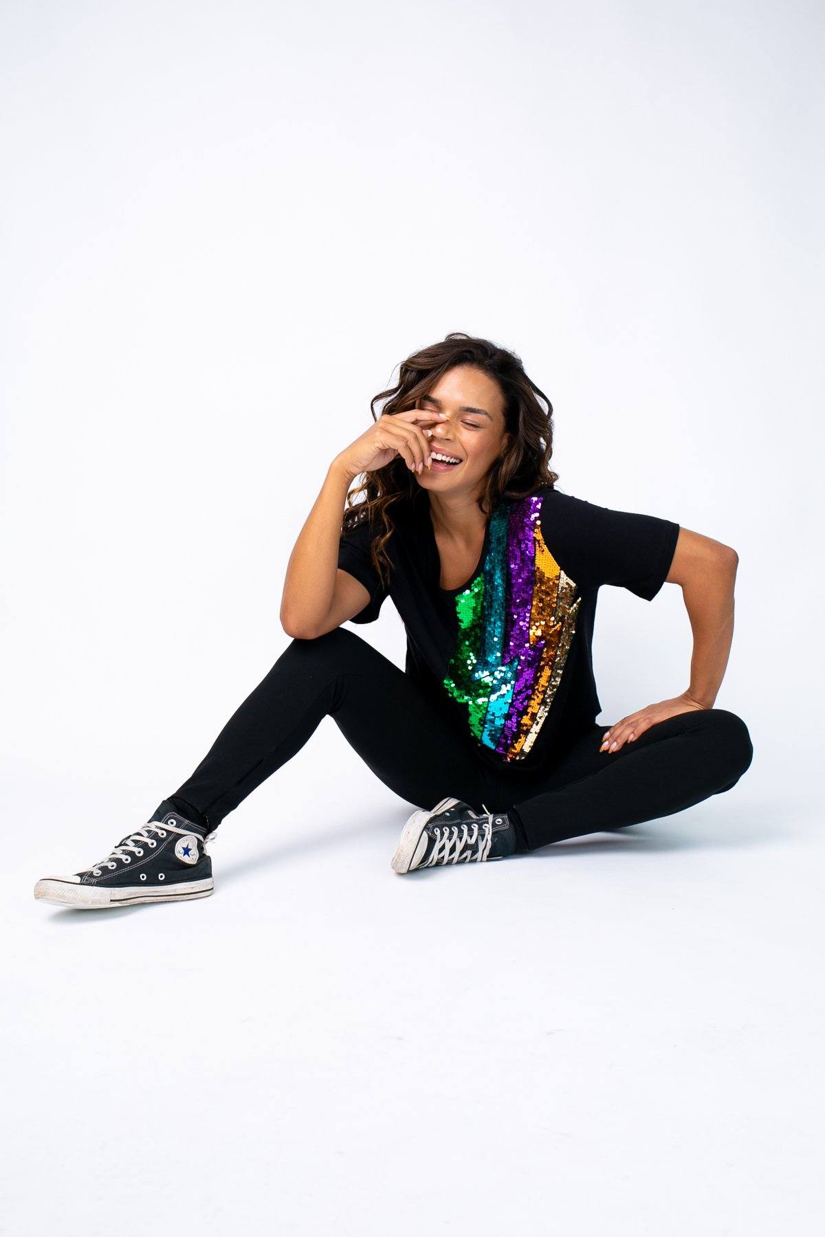Modelo está sentada e usa camiseta raio na cor preta. Peça ideal para usar no dia a dia, festas, shows, passeios ou eventos.