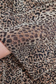 A imagem mostra o tecido do vestido onça de malha lurex com estampa de animal print de oncinha dourado. Tecido possui brilho 